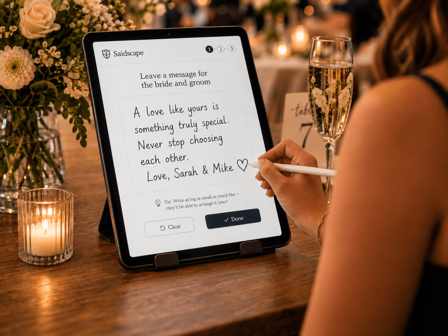 A guest writing a handwritten message on a tablet at a wedding celebration